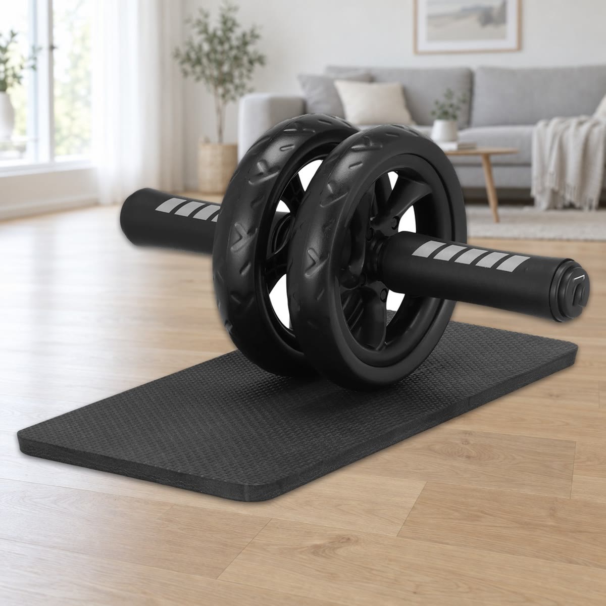 Ab wheel med to hjul på 15 cm og skumhåndtak, stående på den svarte knematten på et lyst parkettgulv