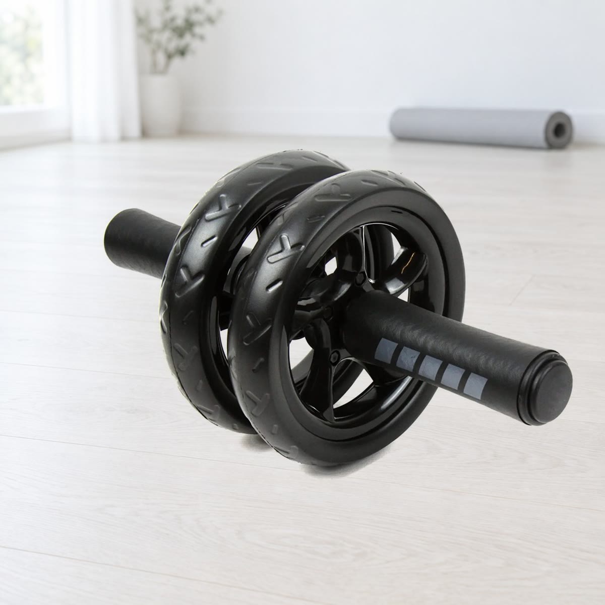 Ab wheel med to svarte, mønstrede hjul og skumhåndtak med grå striper, på et lyst tregulv