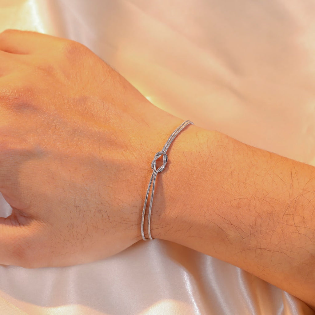 Det sølvfargede armbåndet på en manns håndledd