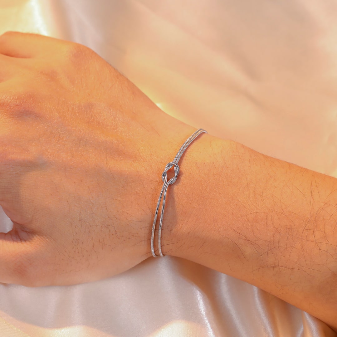 Det sølvfargede armbåndet på en manns håndledd