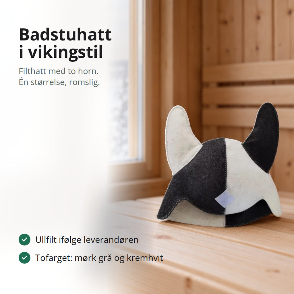 Badstuhatt i filt med to horn, tofarget i mørk grå og kremhvit, stående på en badstubenk ved et vindu mot en snødekt innsjø
