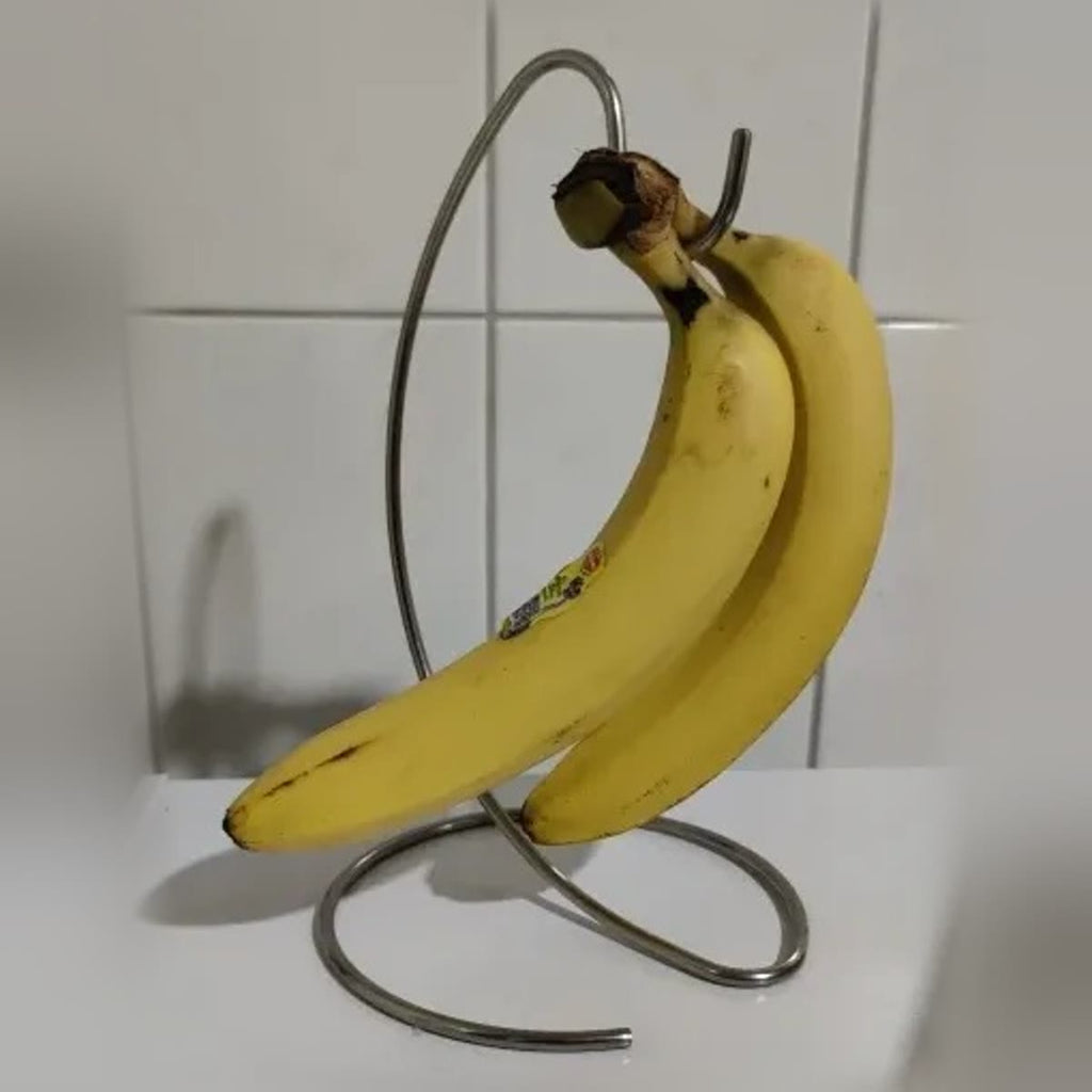 Kjøperbilde: to bananer på kroken; stativet står på en hvit benk foran hvite fliser