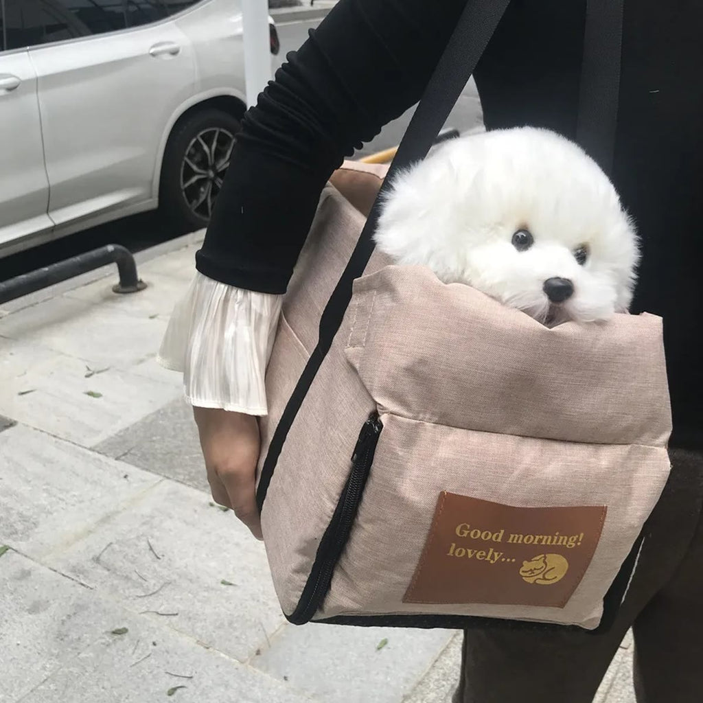 Bilsetet i kaki båret over skulderen som en veske, med en tøyhund i