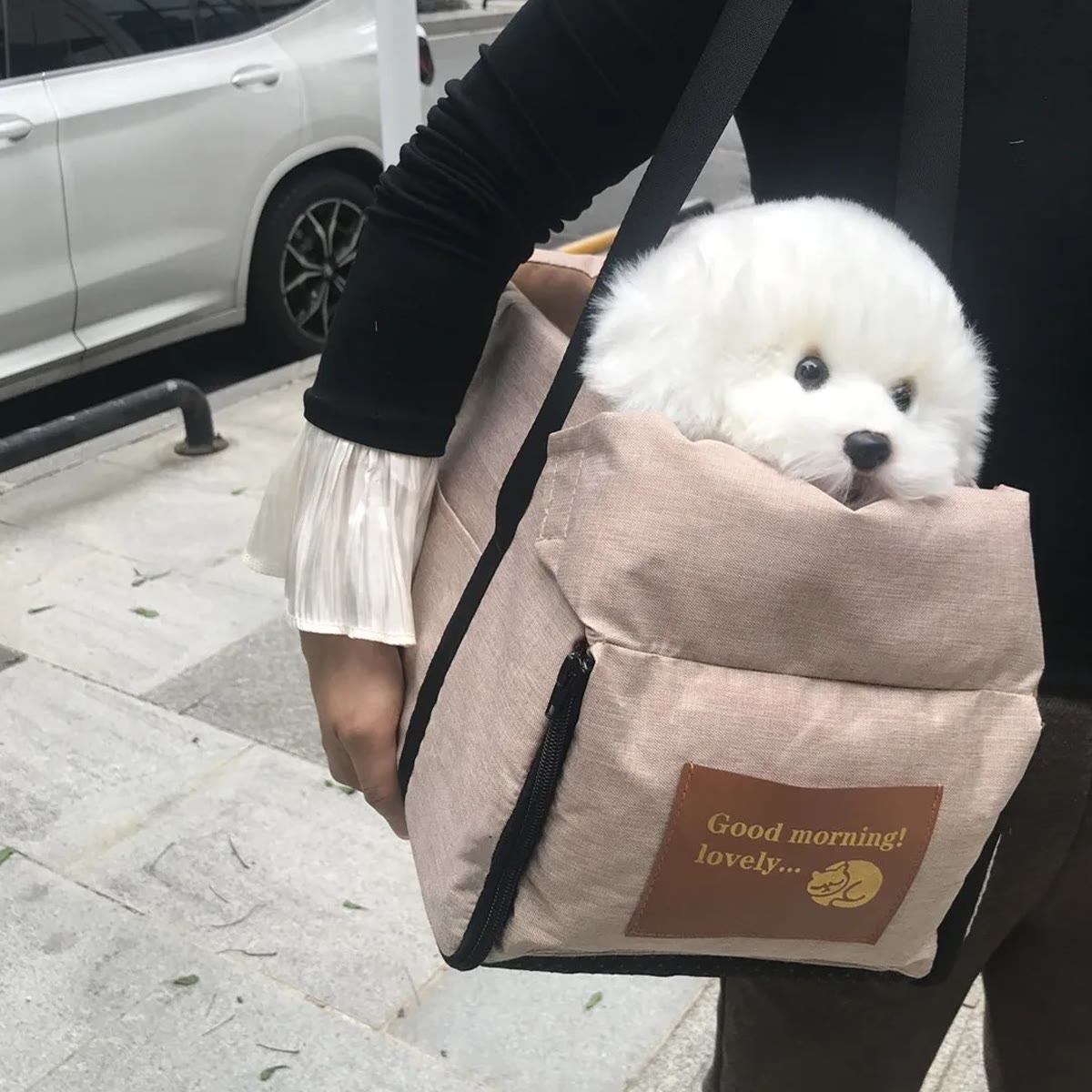 Bilsetet i kaki båret over skulderen som en veske, med en tøyhund i