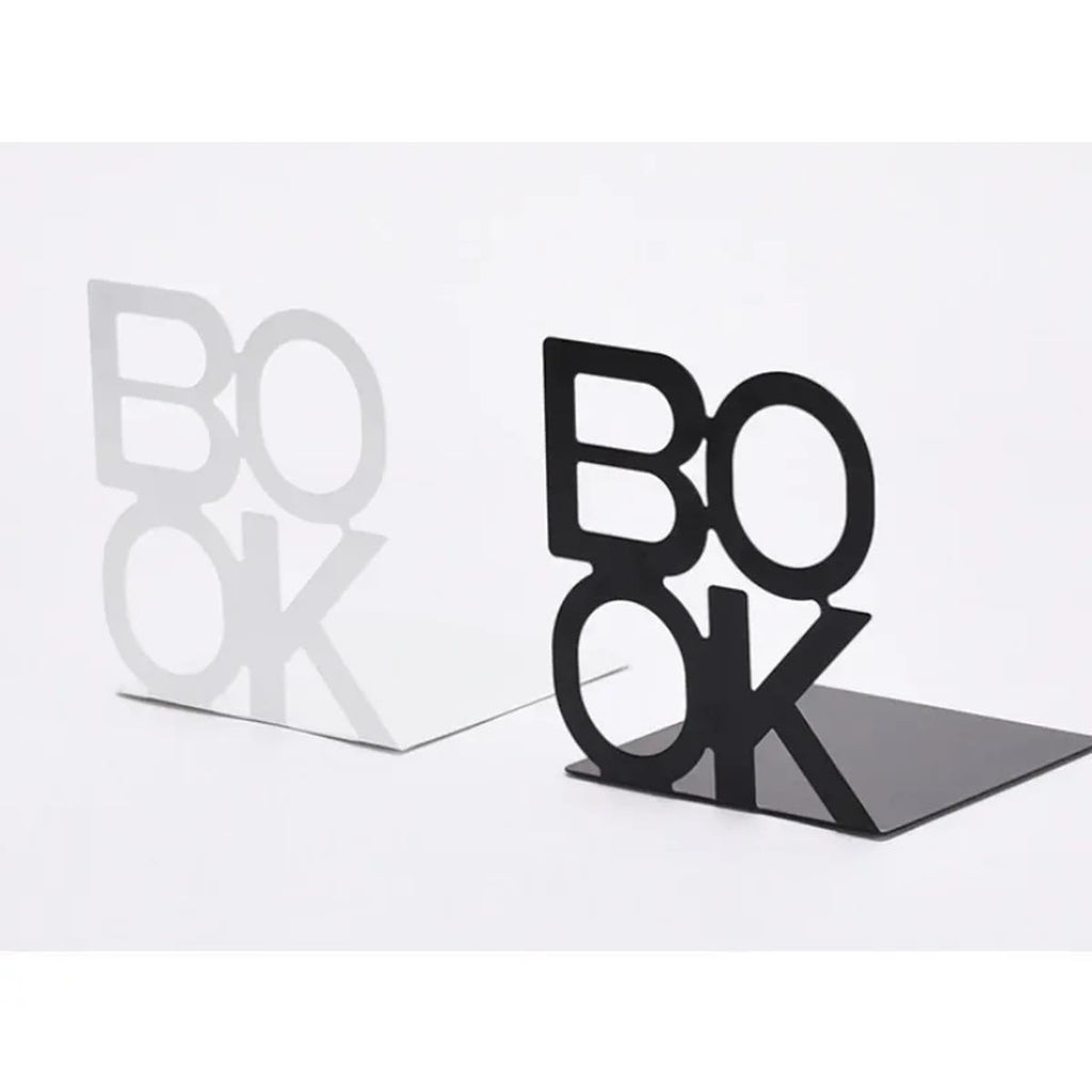 Hvit og svart bokstøtte i metall med bokstavene BOOK side om side