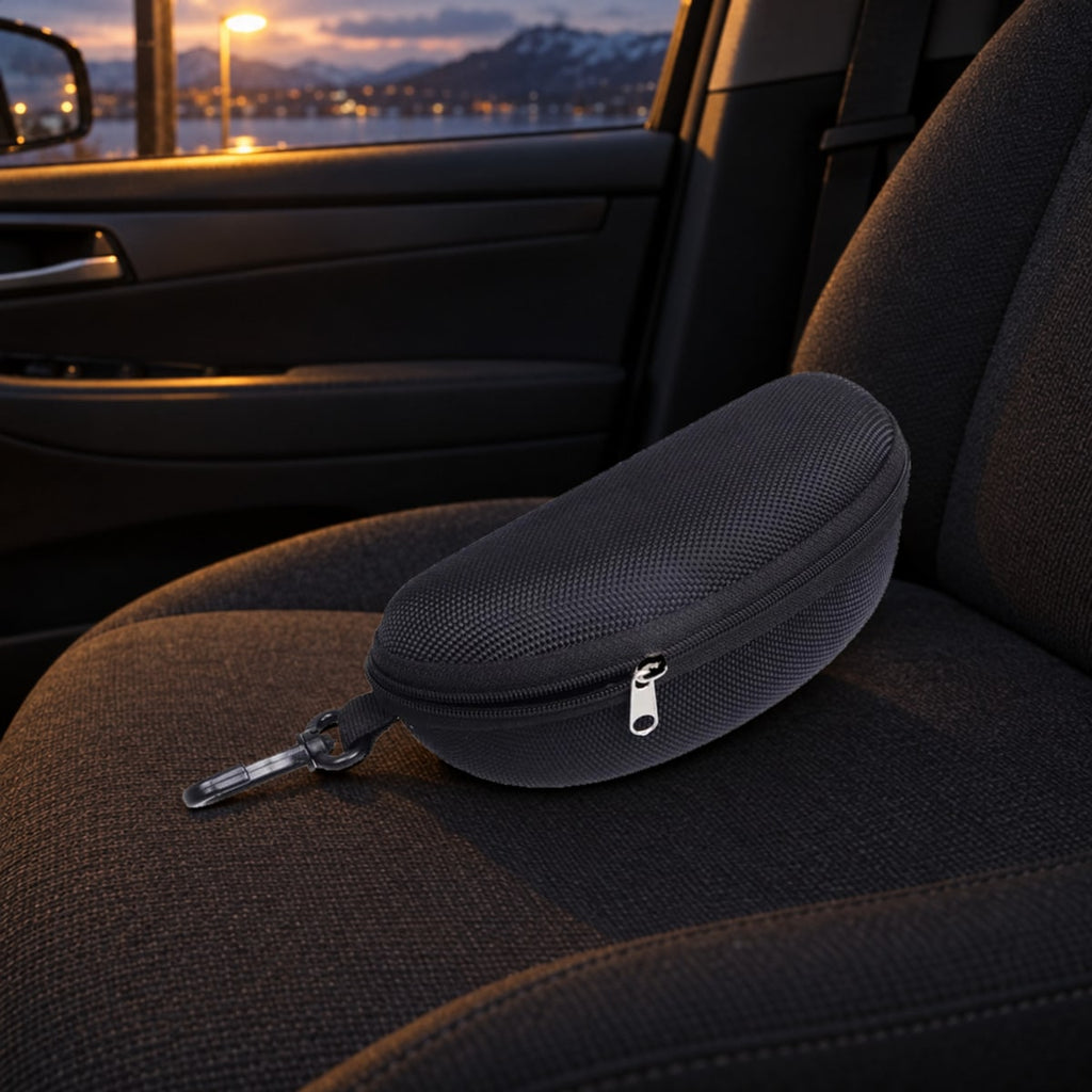 Svart hardt brilleetui med glidelås og karabinkrok på passasjersetet i bilen en kveld