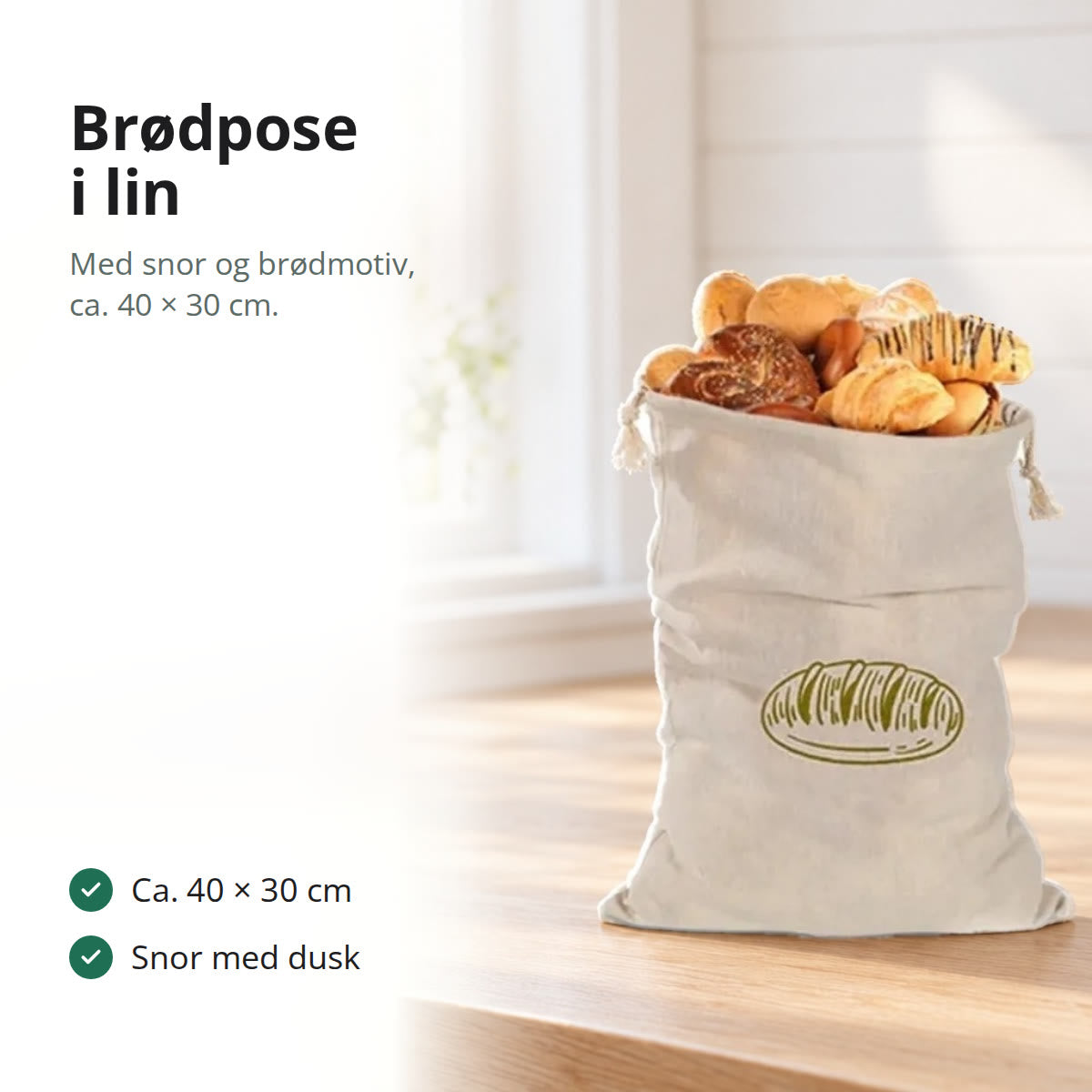 Brødpose i lin med snor og brødmotiv, fylt med brød og wienerbrød, på en kjøkkenbenk av eik