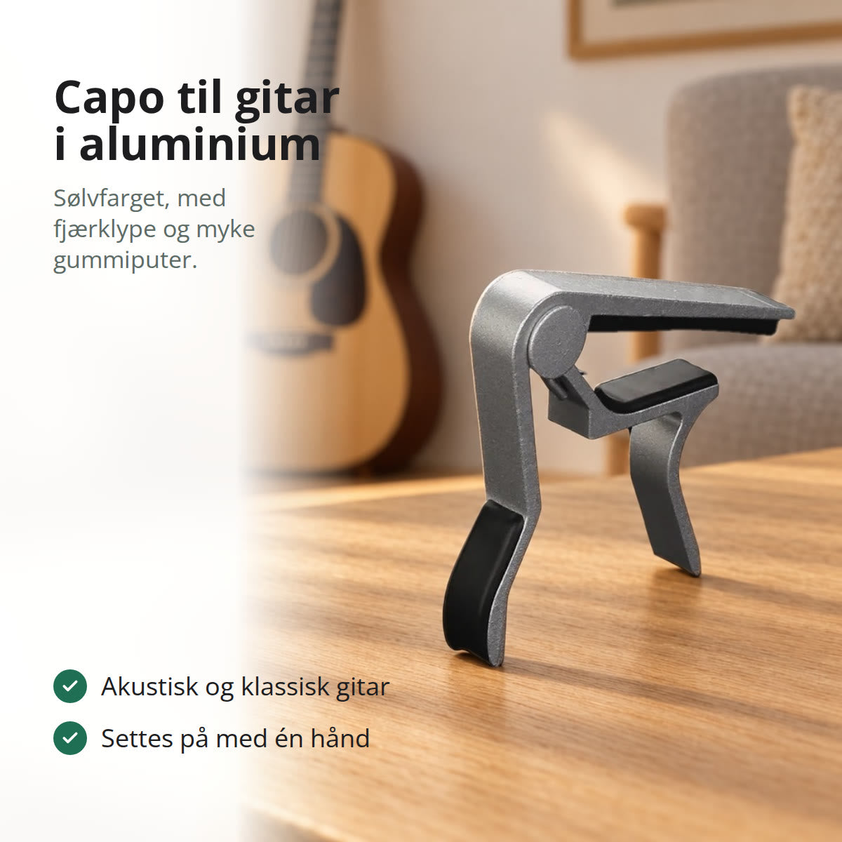 Sølvfarget capo til gitar i aluminium som står på et eikebord i en stue, med en akustisk gitar i bakgrunnen