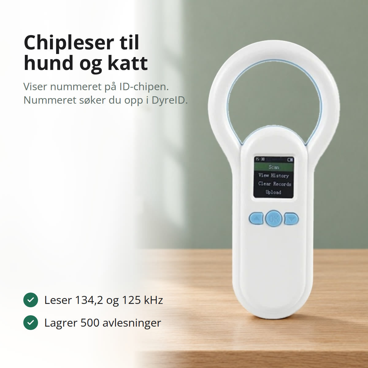 Hvit chipleser til hund og katt med ringformet antenne og fargeskjerm, stående på et eikebord foran en grønn vegg