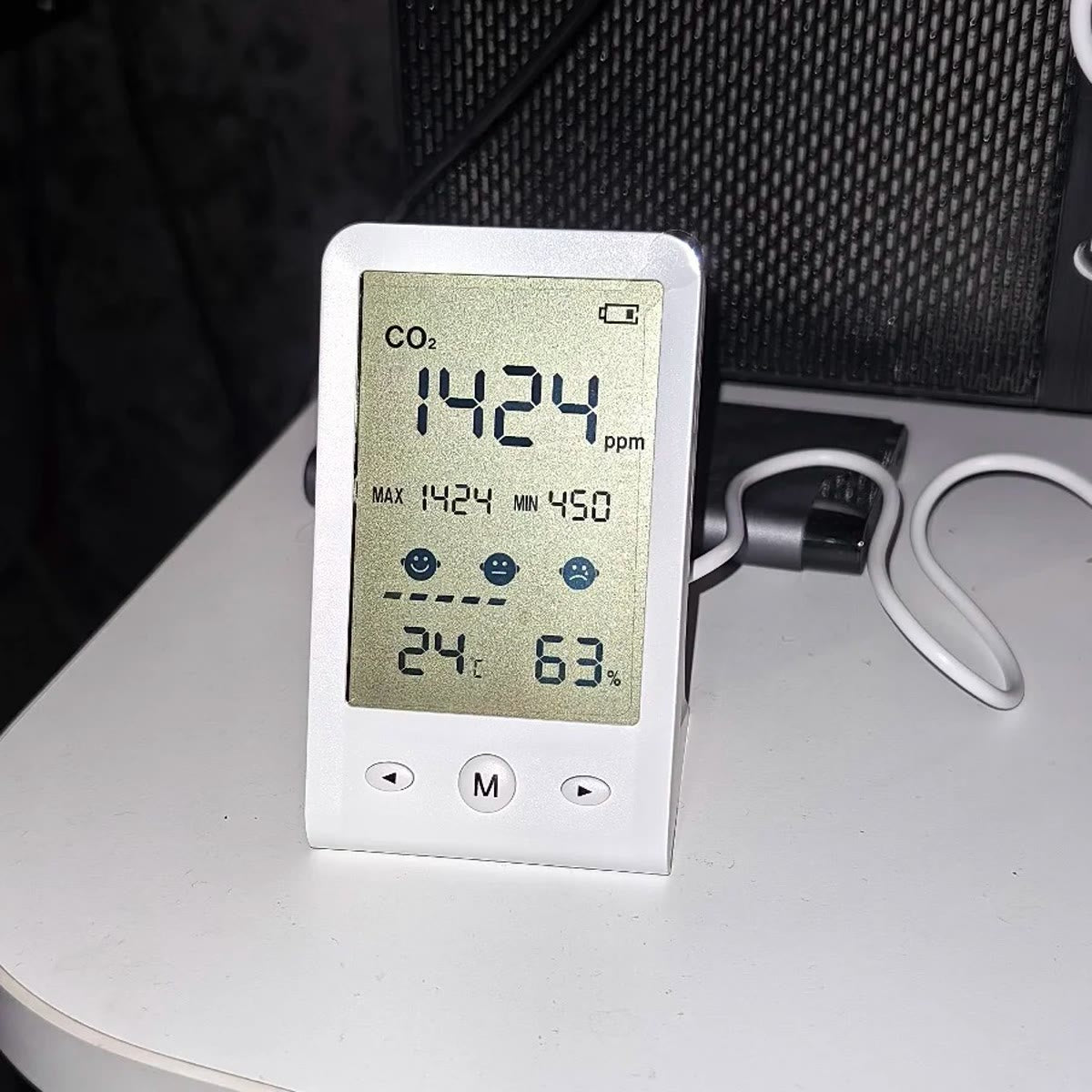 Kjøperbilde: CO2-måleren på et hvitt skrivebord om kvelden, koblet til strøm, med CO2, temperatur og luftfuktighet på skjermen
