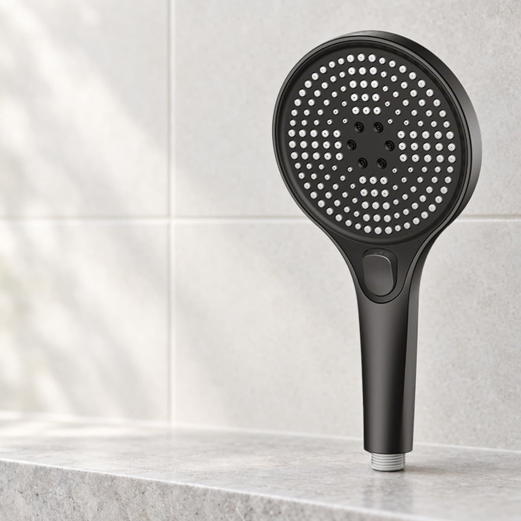 Svart dusjhode med rundt dysepanel på en steinhylle i badet