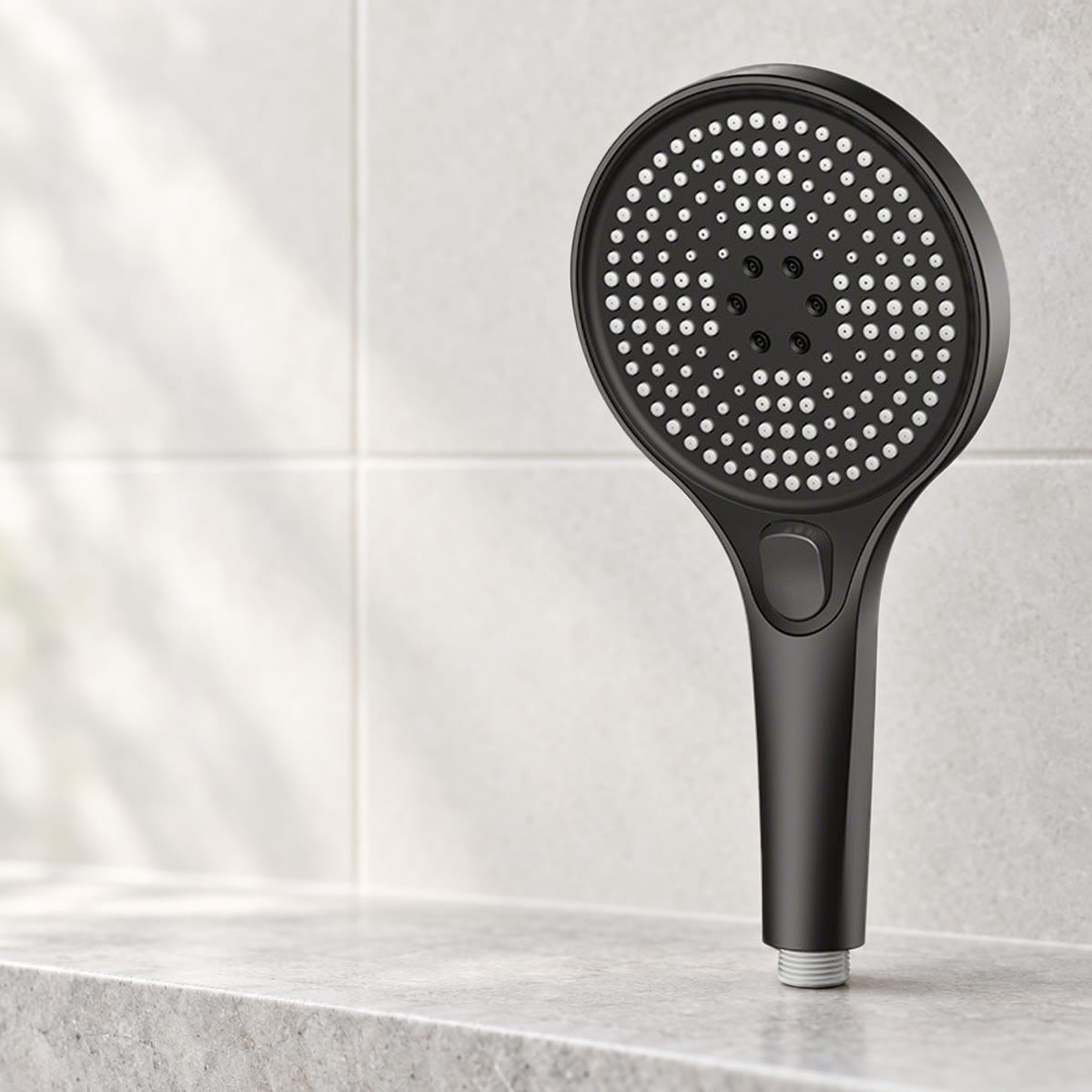 Svart dusjhode med rundt dysepanel på en steinhylle i badet