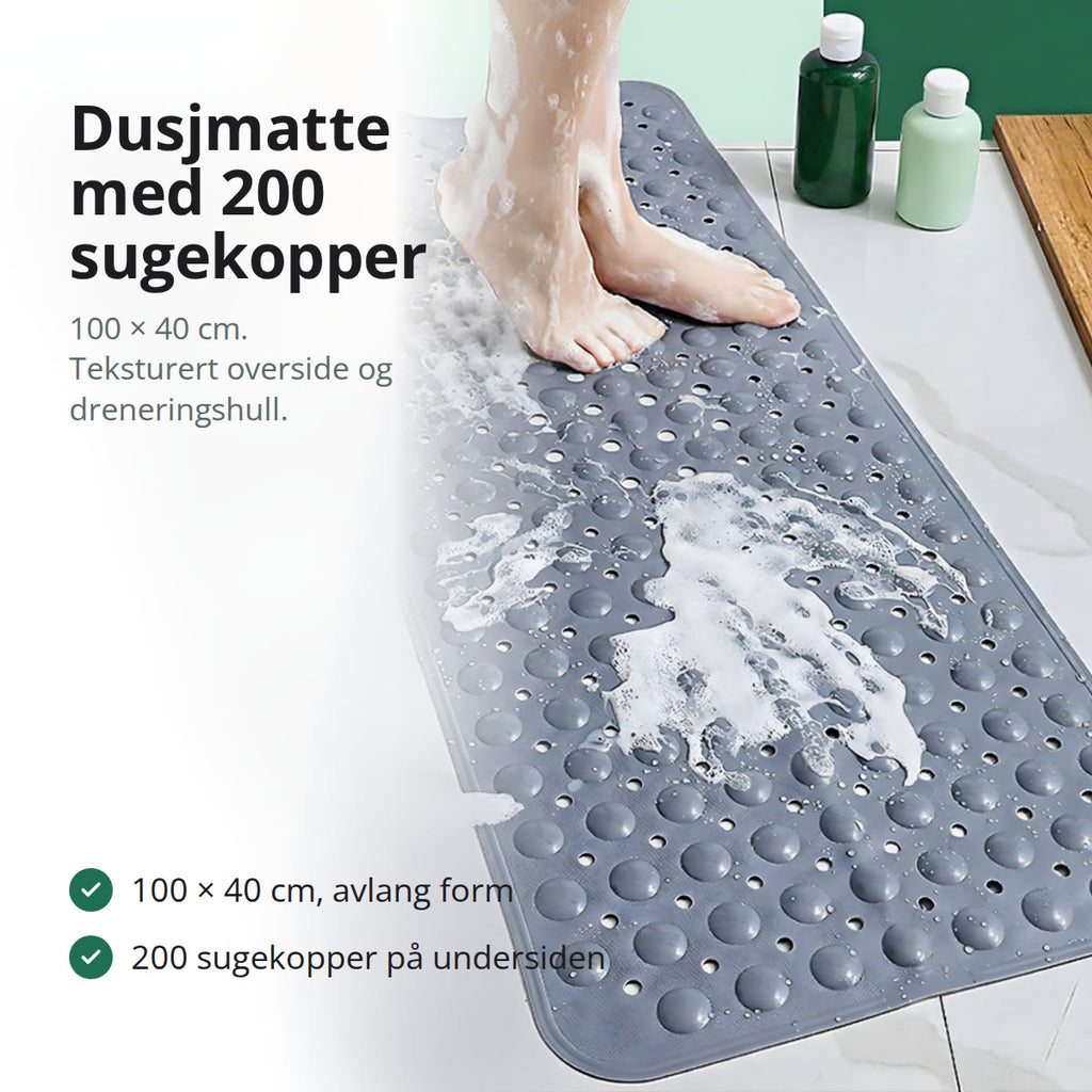 Grå sklisikker dusjmatte liggende på badegulvet ved siden av et hvitt badekar