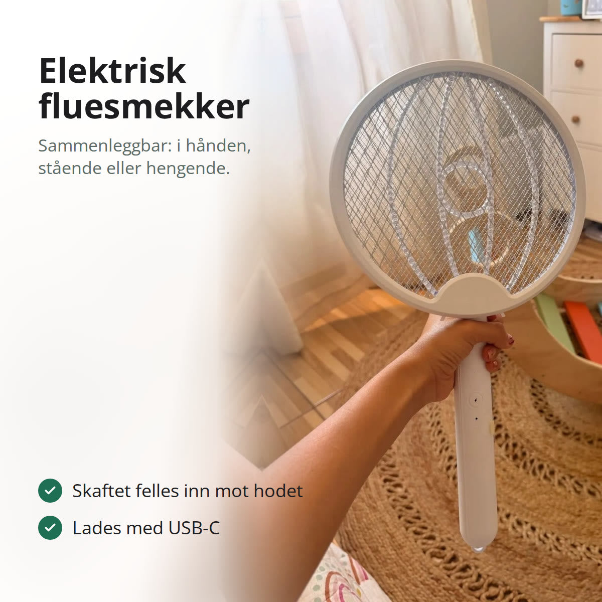 Hvit elektrisk fluesmekker med rundt nett, holdt i hånden i et lyst rom med jutematte på gulvet
