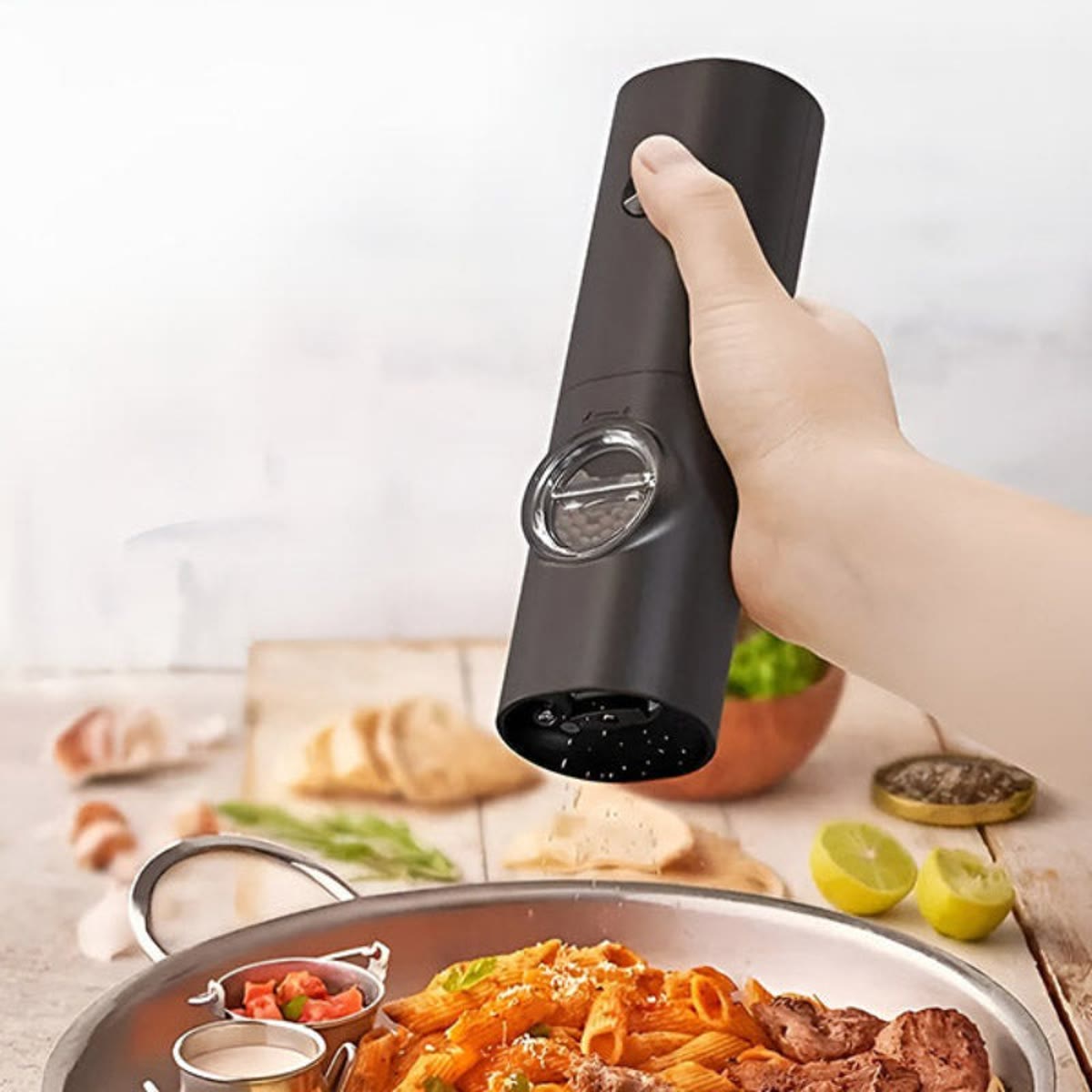 Kvernen holdt i én hånd og brukt over en panne med pasta