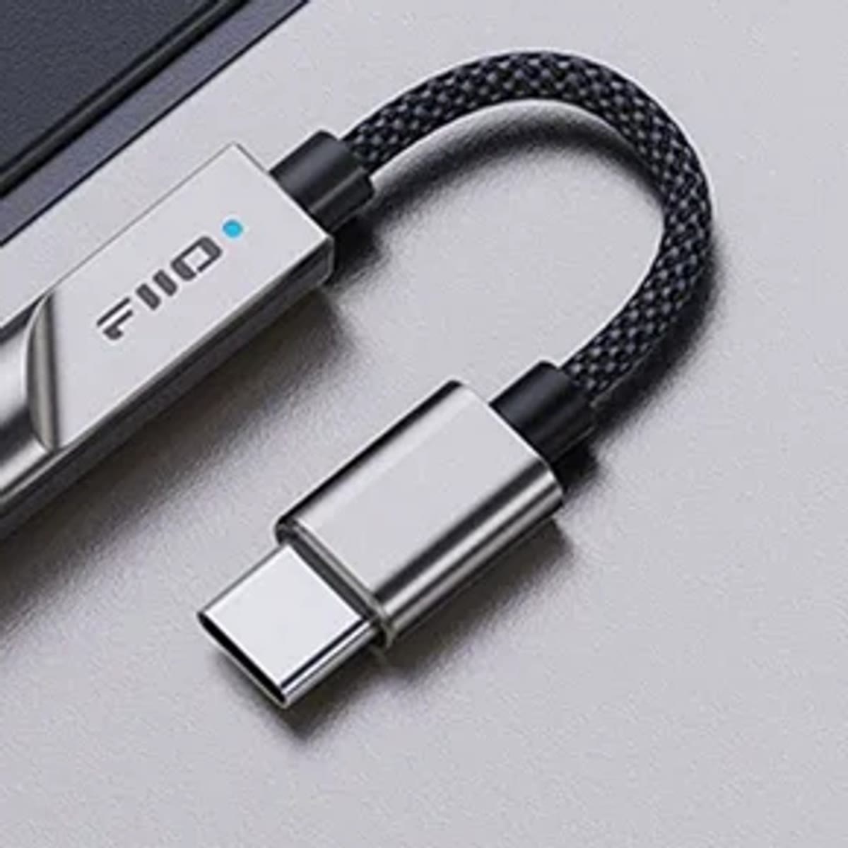 Nærbilde av KA11 med blått lys på kabinettet, fast flettet kabel og USB-C-plugg i metall