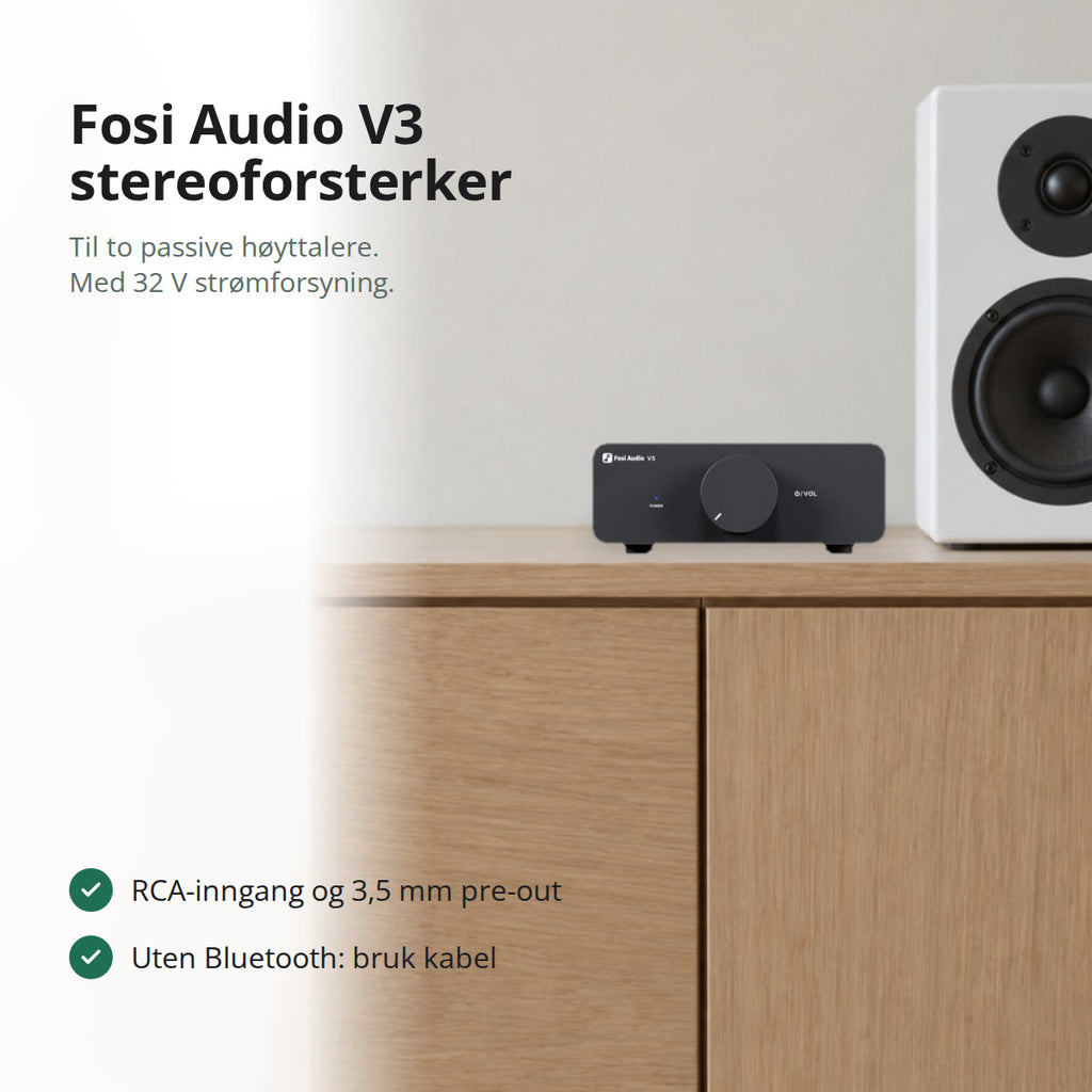 Svart V3 stereoforsterker på en lys eikeskjenk ved siden av en hvit stativhøyttaler, sett rett forfra