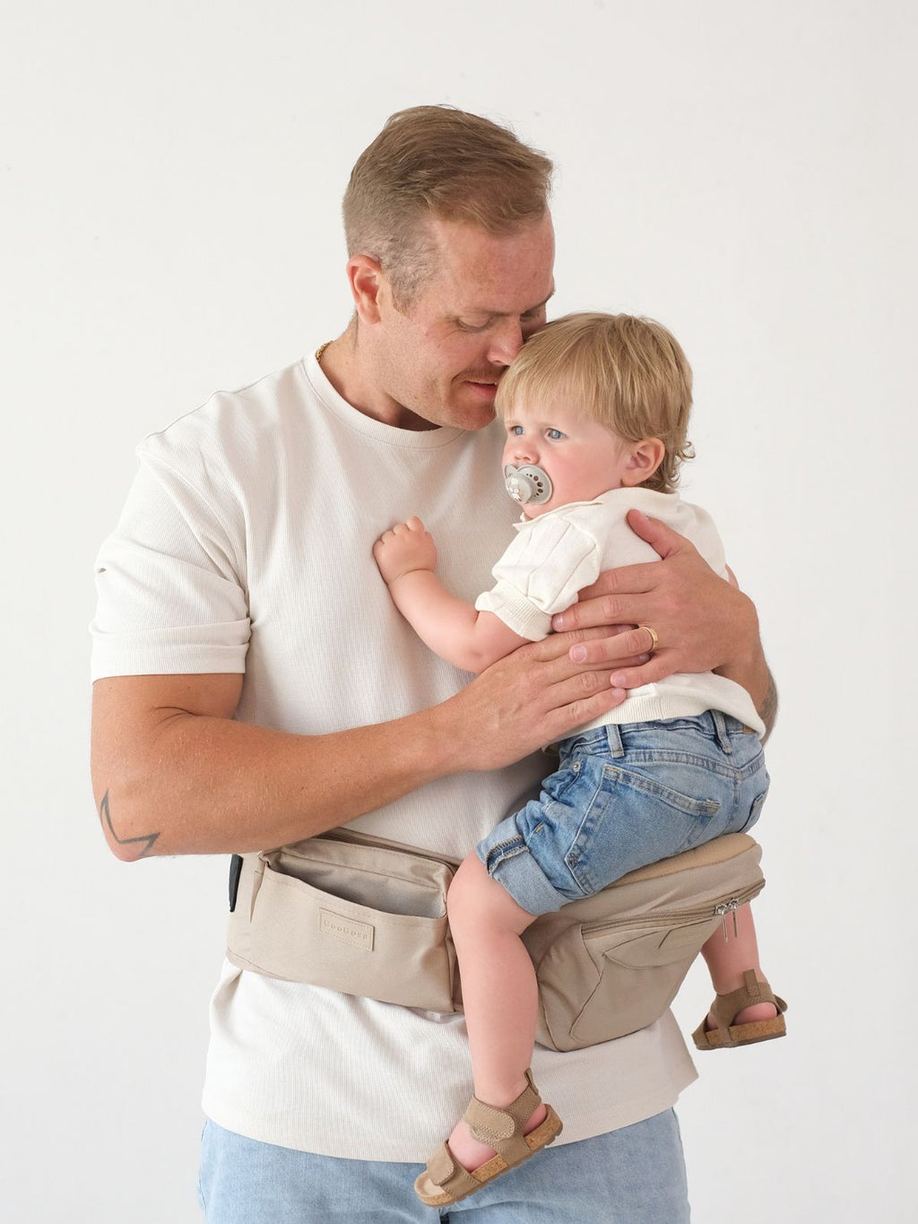 Far baerer barn med GooGosa hoftbaerer sand