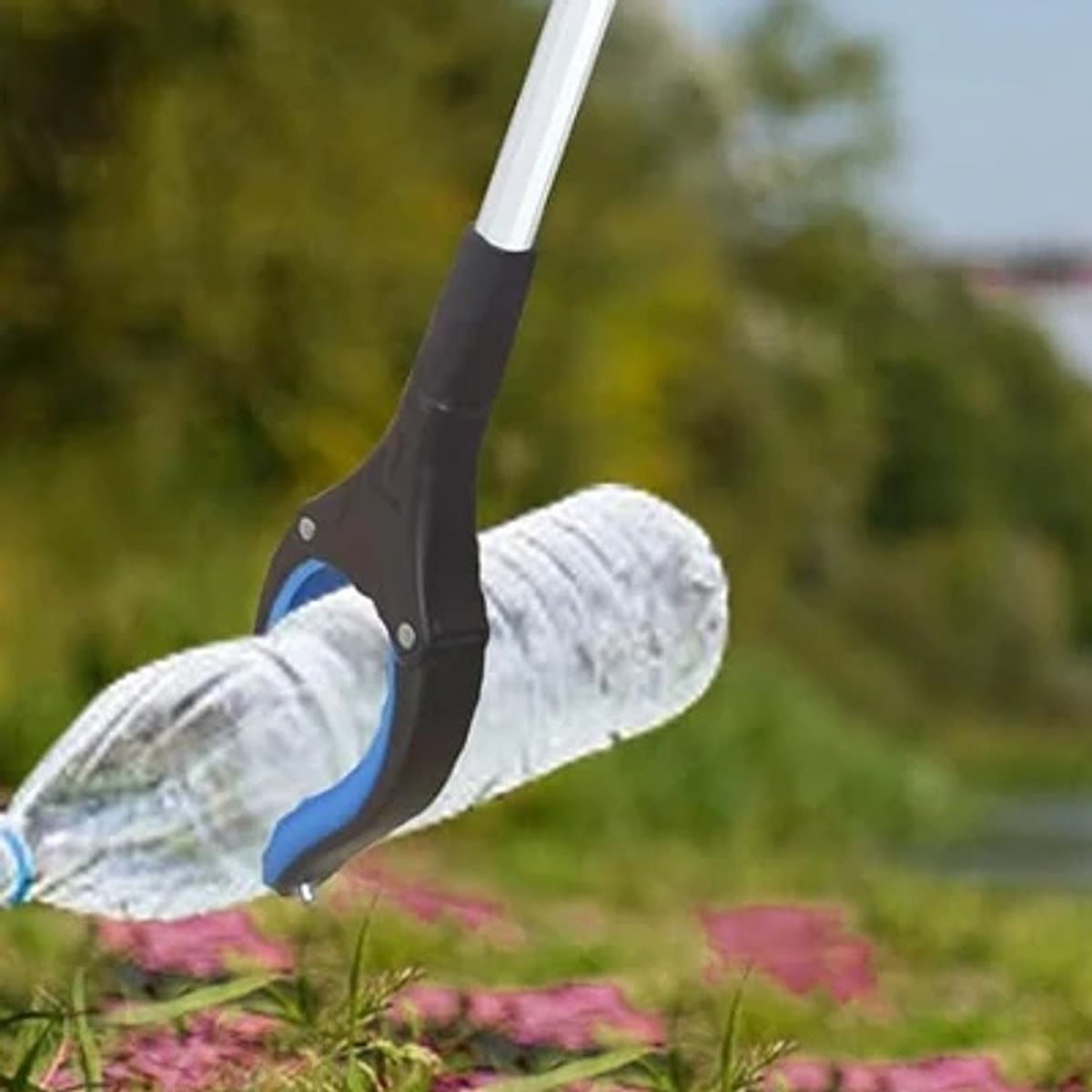 Gripetangen plukker opp en tom plastflaske fra gresset ute