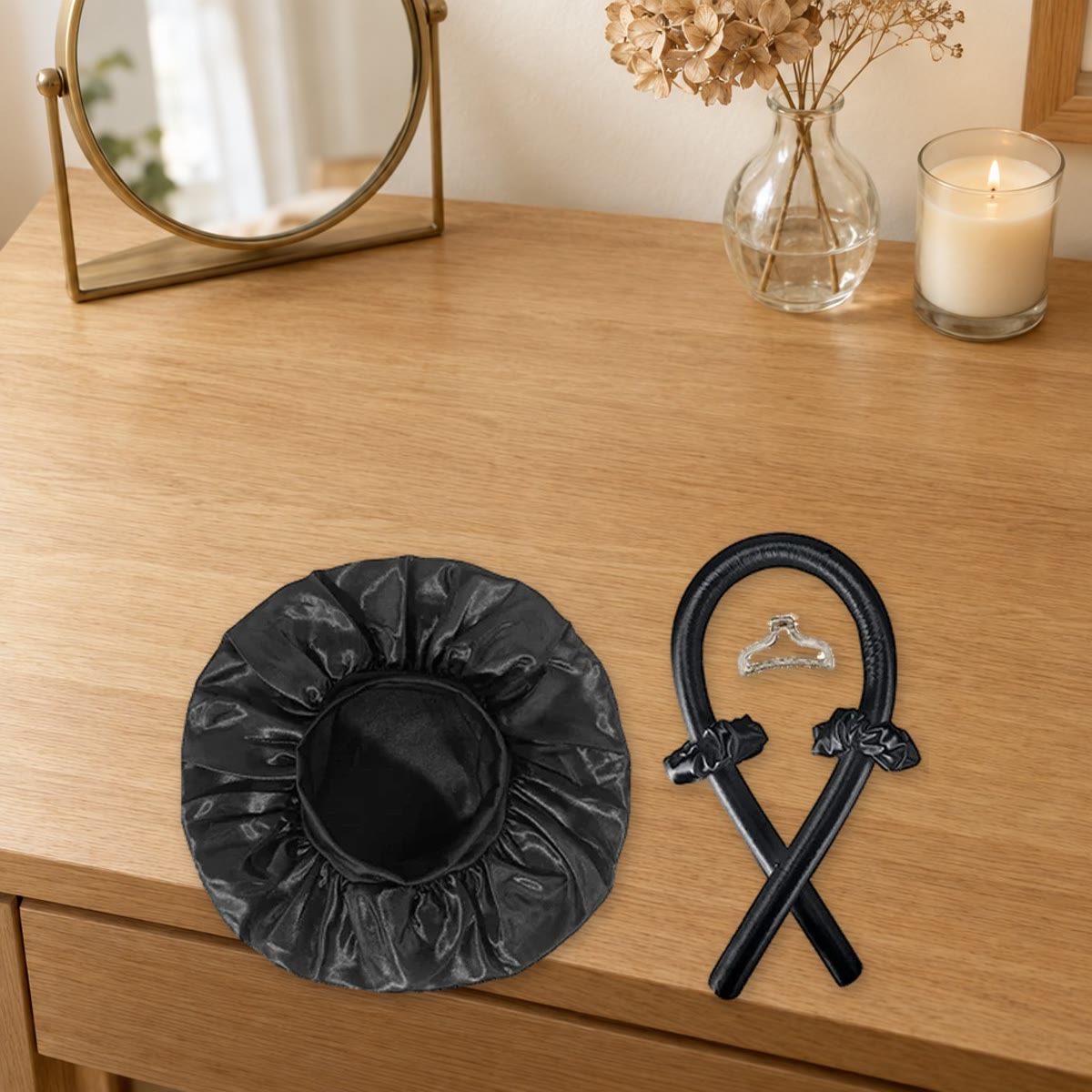 Heatless curls-sett i svart: krøllestav, satenghette, scrunchies og hårklype på et sminkebord