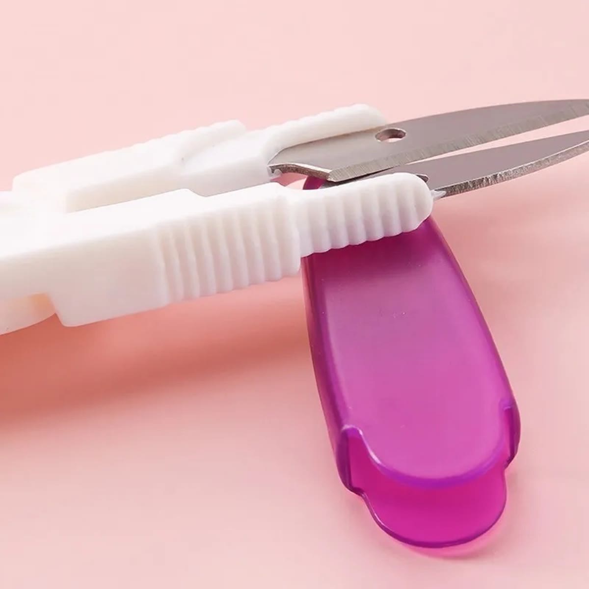 Liten trådsaks med hvitt håndtak og lilla beskyttelseshette fra heklenålsettet