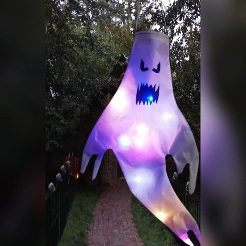 Tent halloween spøkelse med sint ansikt og lilla og hvite LED-lys, hengende over en hagesti om kvelden
