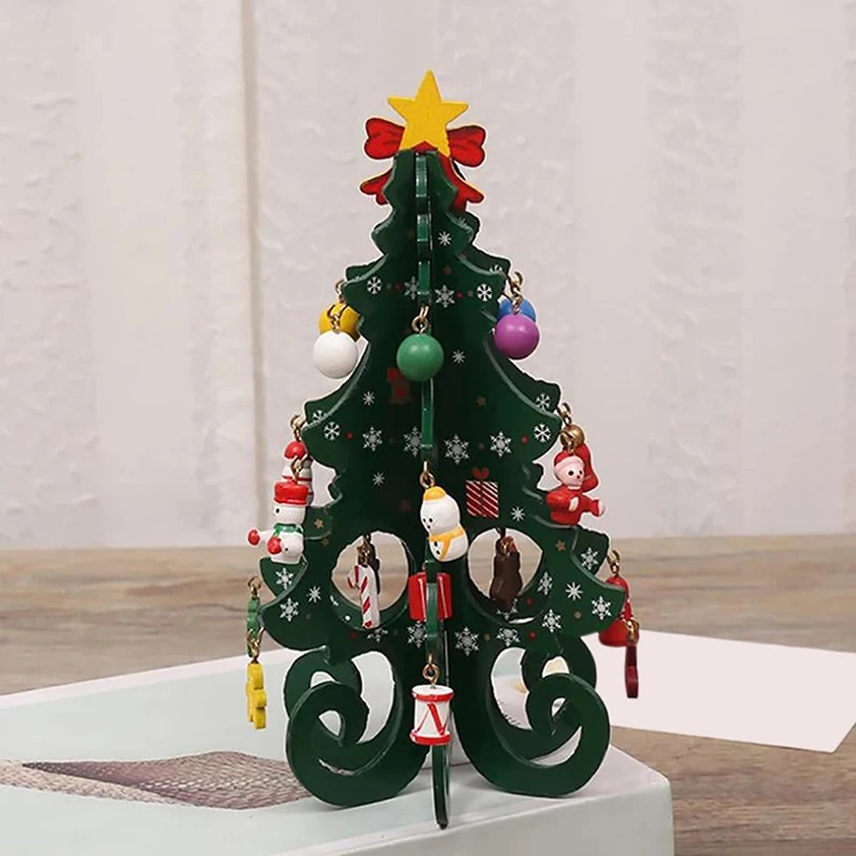 Grønt juletre i tre med snøfnugg-trykk og små figurer og kuler i tre