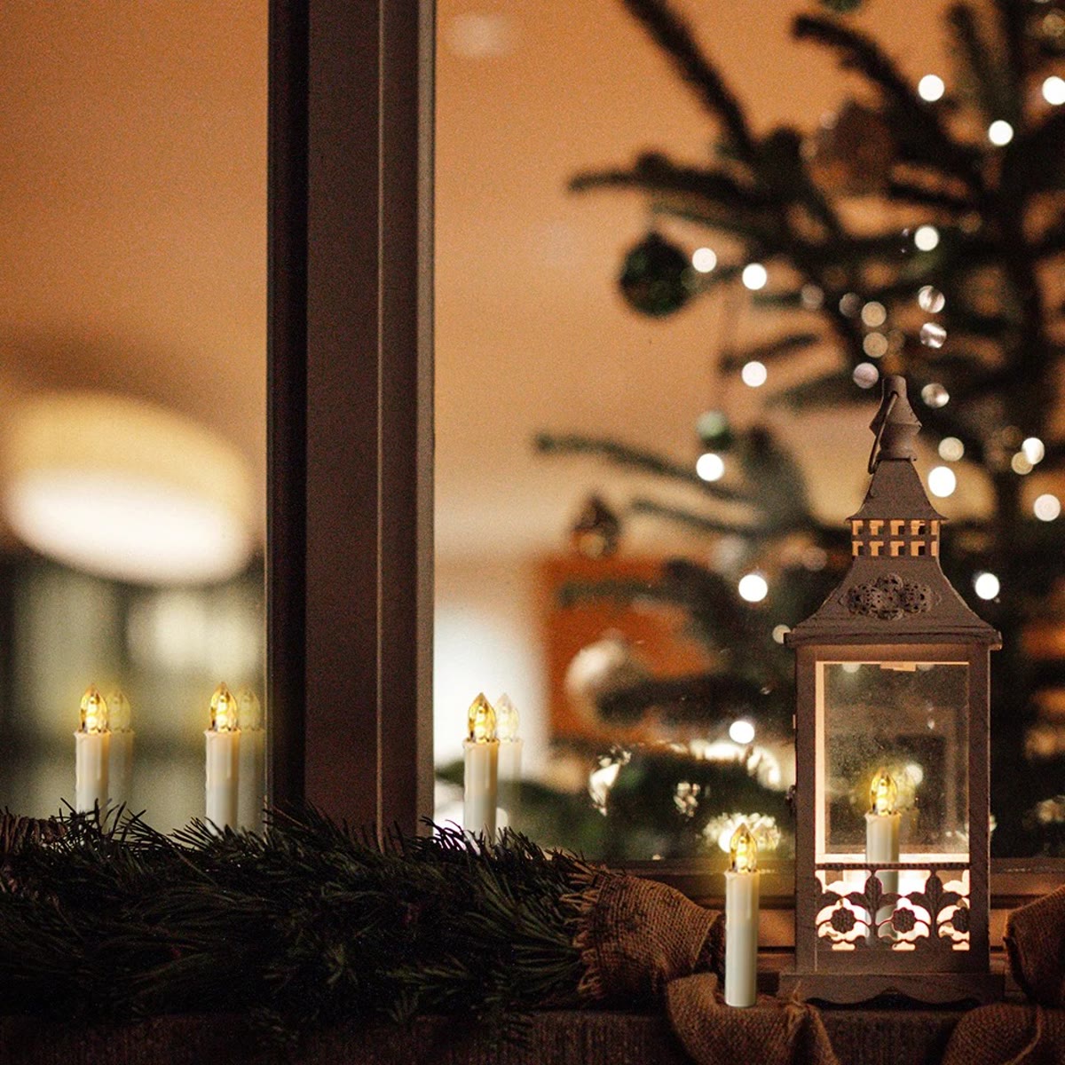 Juletrelysene stående i en vinduskarm ved siden av en lykt, uten klype