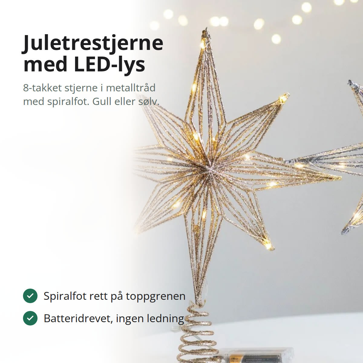 Juletrestjerne i gullfarget metalltråd med LED-lys og spiralfot, stående på et bord ved siden av julekuler