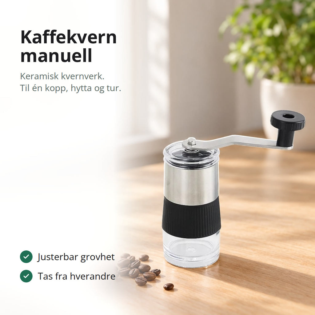 Manuell kaffekvern i rustfritt stål med svart grep og sveiv på et trebord ved et vindu