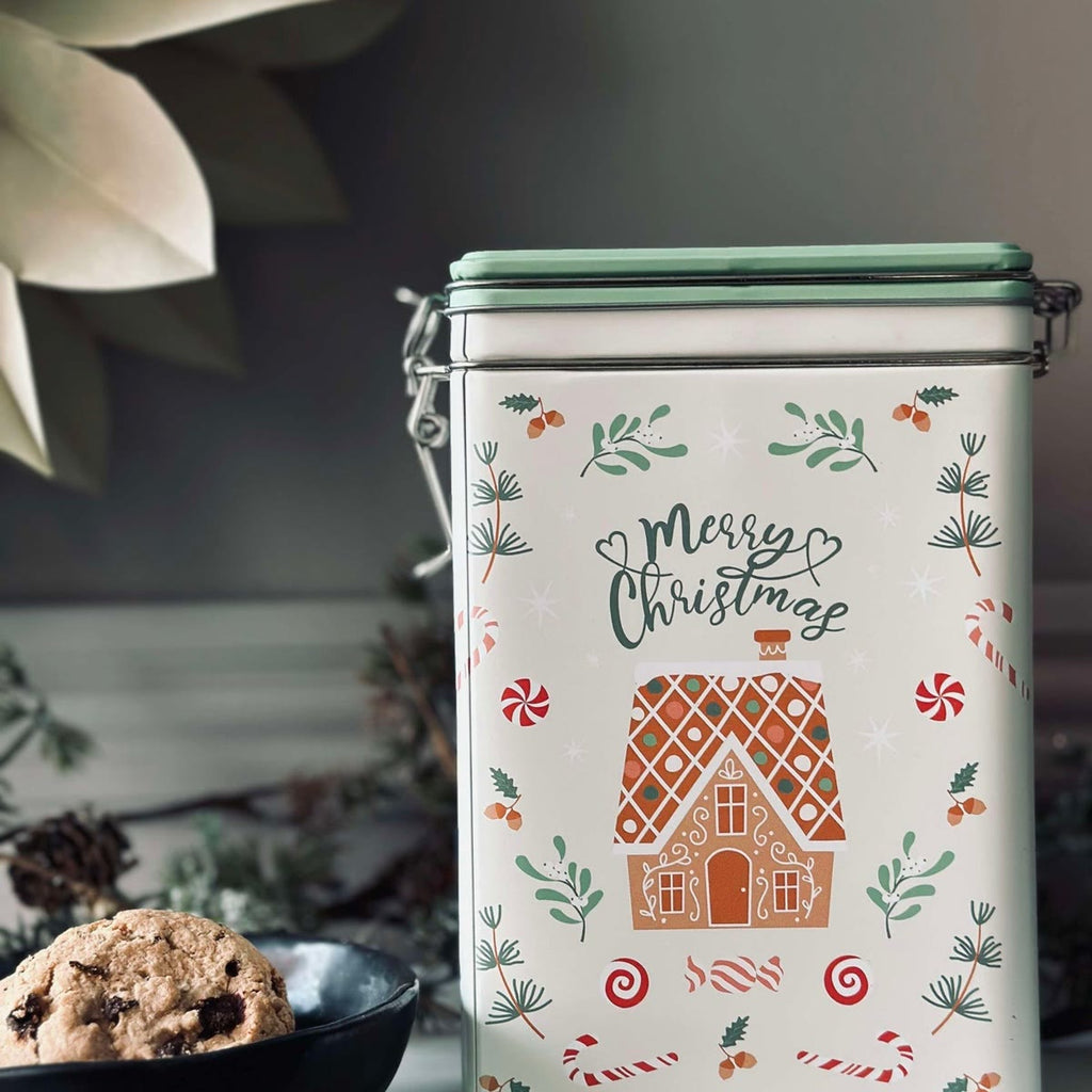 Kakeboksen med julemotiv på en benk ved siden av en skål med kjeks