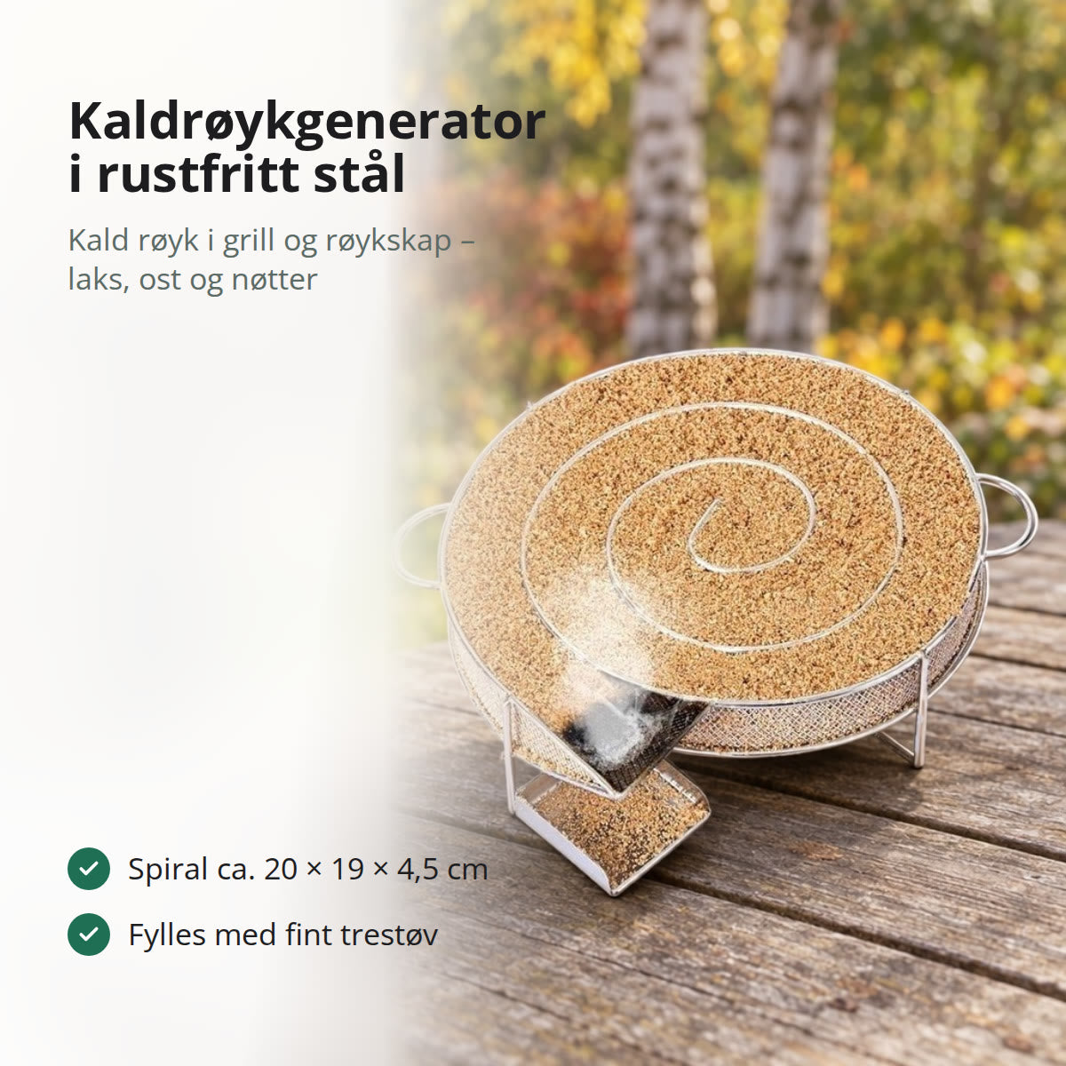 Kaldrøykgenerator i rustfritt stålnett fylt med trestøv, på et værbitt hagebord med høstløv og bjørk i bakgrunnen