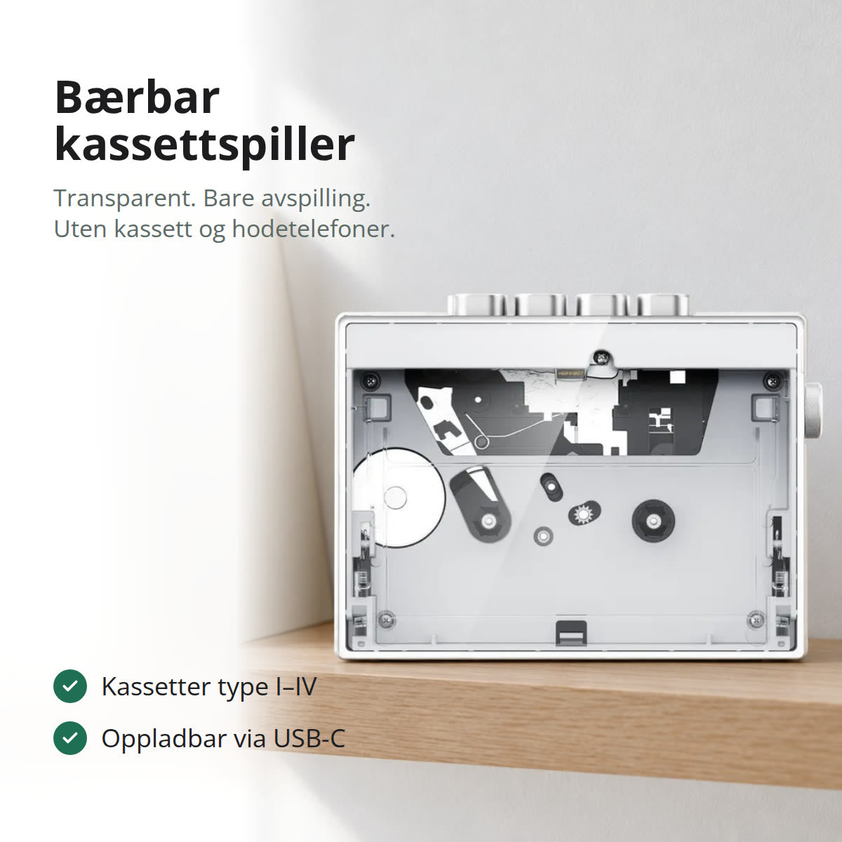 Gjennomsiktig bærbar kassettspiller som står på en hylle i lys eik foran en hvit vegg, med vinylplater i blanke omslag ved siden av