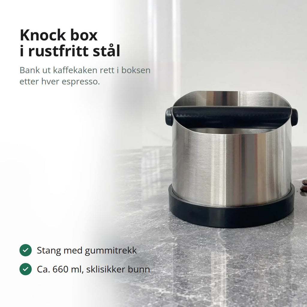 Knock box i rustfritt stål med svart bankestang og svart bunn på en grå marmorbenk