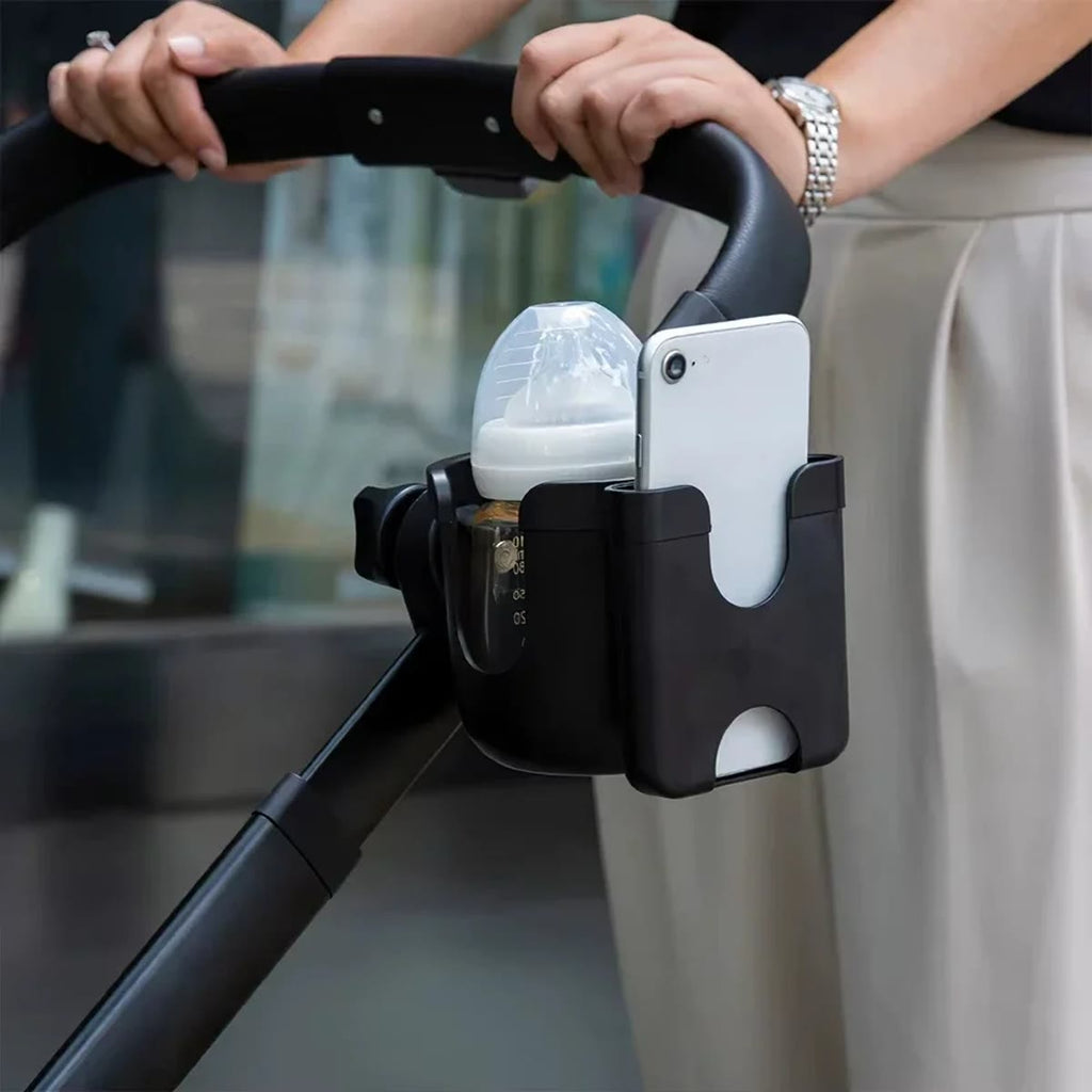 Svart koppholder på håndtaket til en barnevogn med tåteflaske og mobil