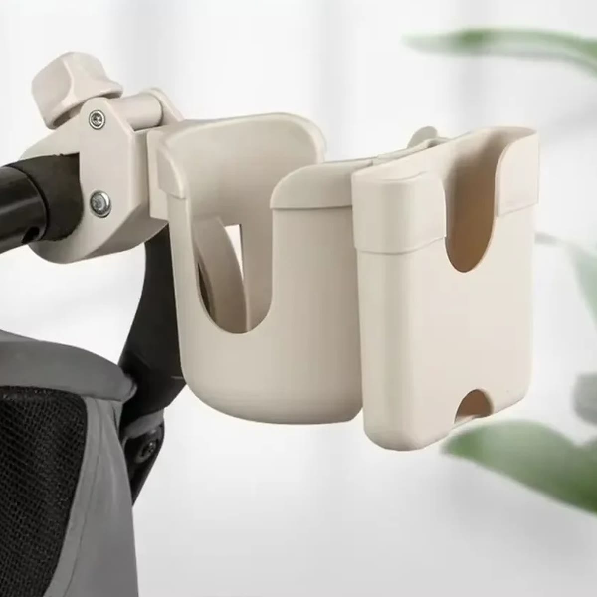 Beige koppholder med mobilholder festet på håndtaket til en barnevogn