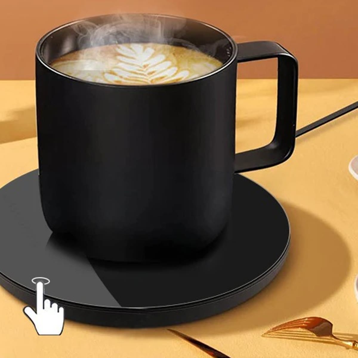 Svart koppvarmer med en kopp kaffe på et bord med småretter, fingeren trykker på touch-knappen