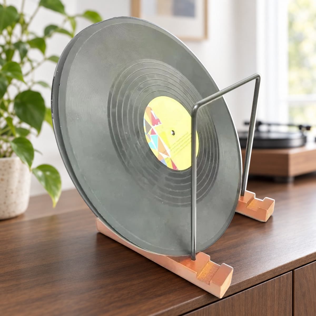 Vinylplate stående i et LP-stativ med føtter i tre og rammer i sort metall på en skjenk i valnøtt