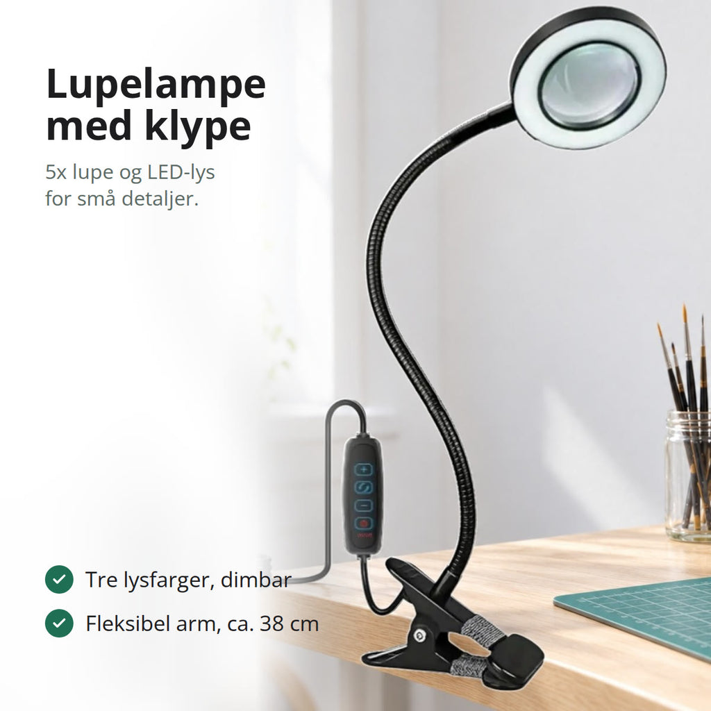 Svart lupelampe med klype, fleksibel arm og lysende LED-ring på et hobbybord med pensler og en figur