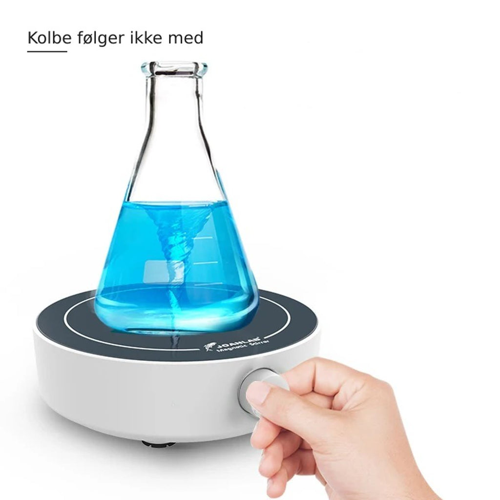 Magnetrøreren i bruk med en erlenmeyerkolbe med blå væske i virvel og en hånd på dreieknappen – kolbe følger ikke med