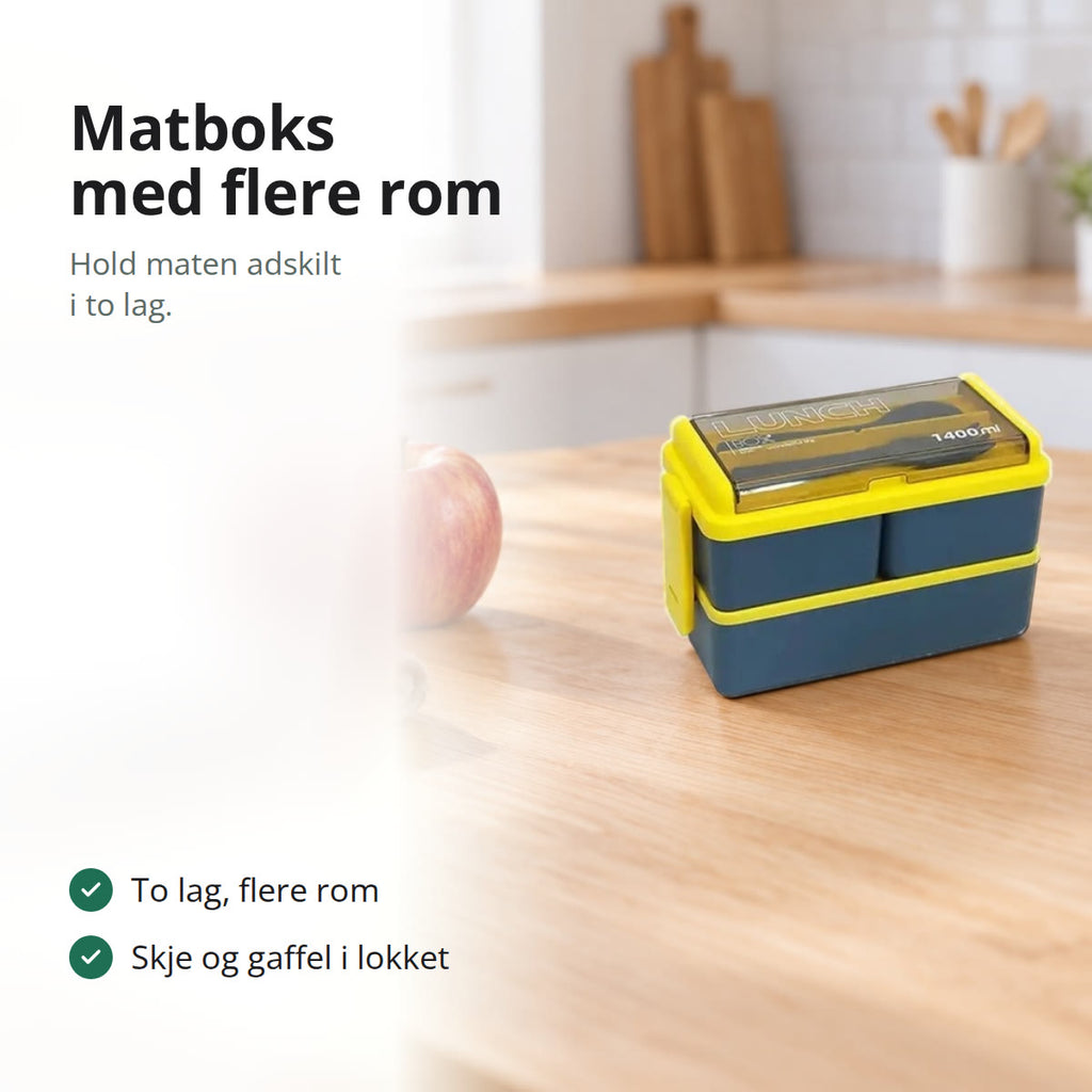Blå matboks med to lag på et kjøkkenbord ved siden av et eple