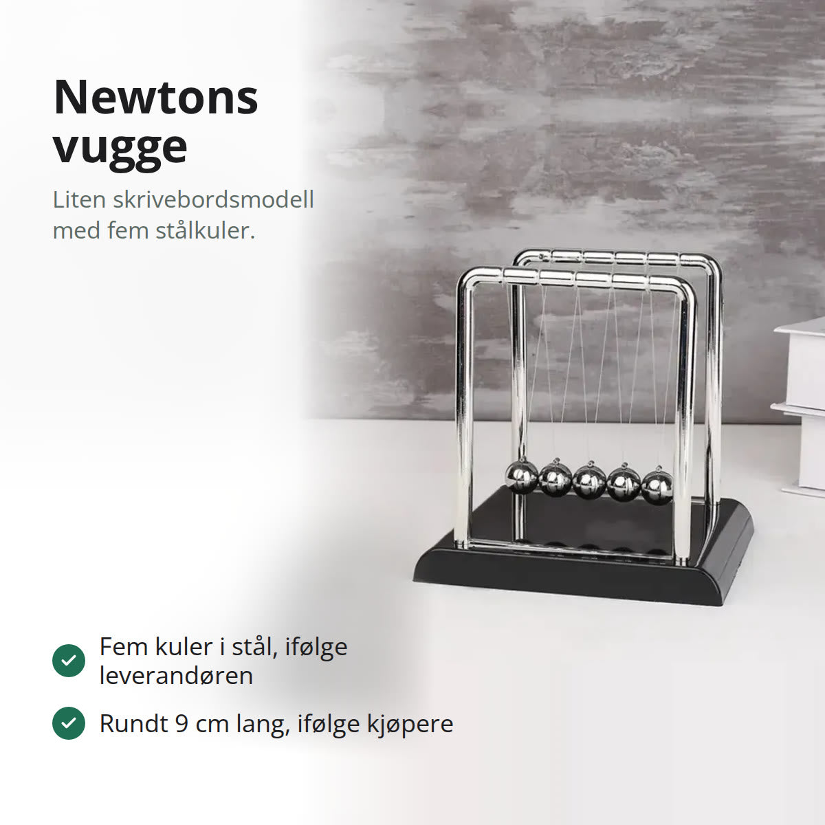 Liten Newtons vugge med fem stålkuler i blank dobbel bøyle på svart sokkel, på et hvitt bord foran en grå vegg