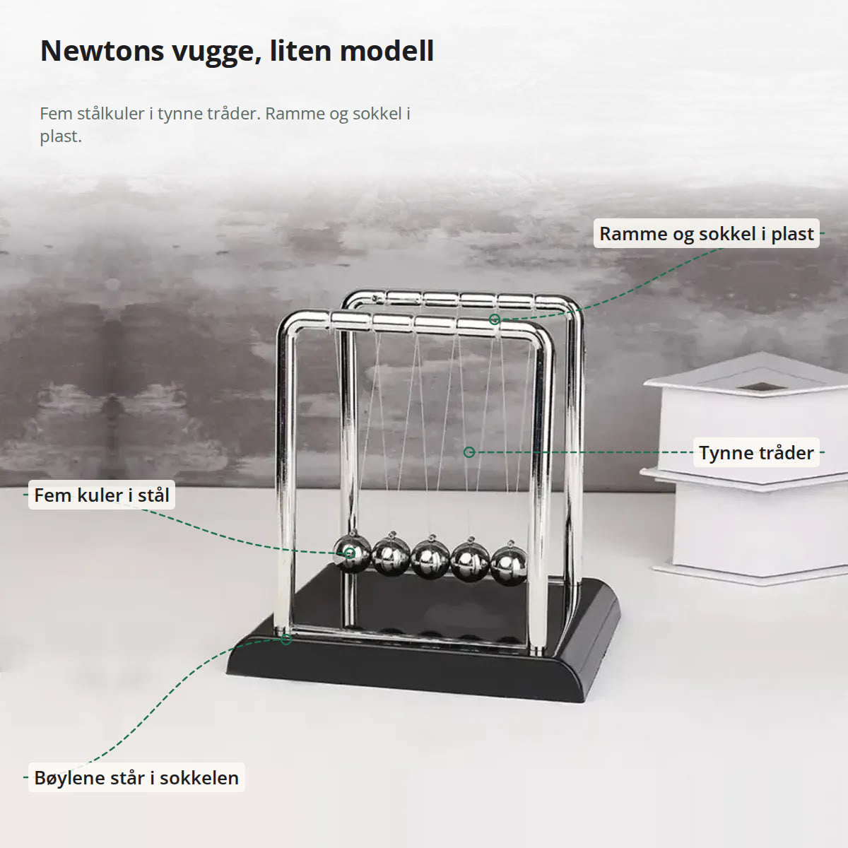 Newtons vugge merket med ramme og sokkel i plast, fem kuler i stål, tynne tråder og bøyler som står i sokkelen