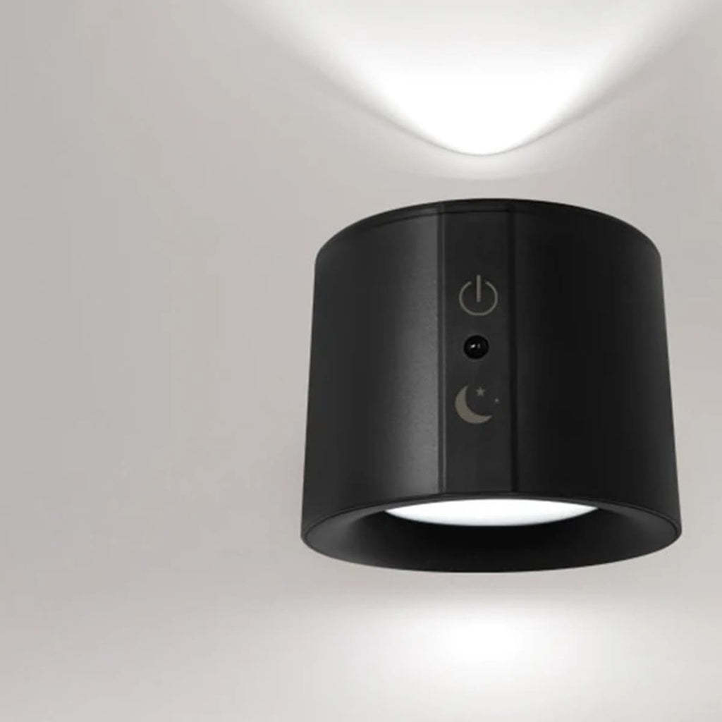 Svart vegglampe på en lys vegg som lyser både oppover og nedover