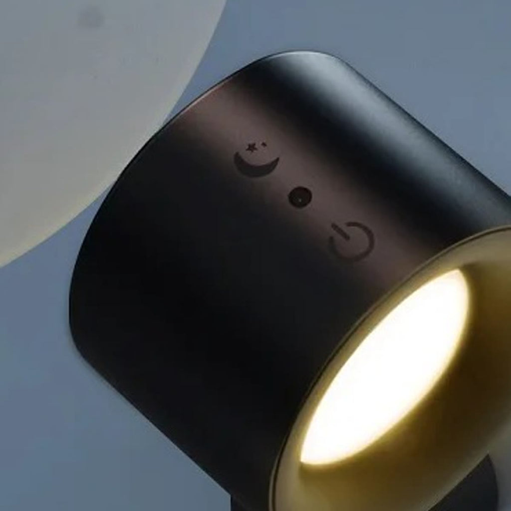 Svart vegglampe med varmt lys på en blågrå vegg