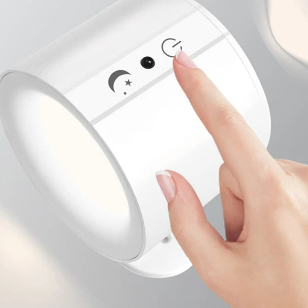 Hvit vegglampe der en finger trykker på touch-knappen på siden