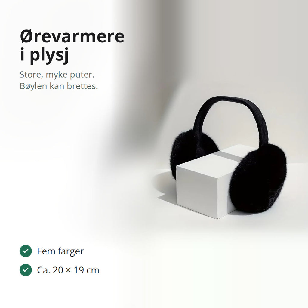 Svarte ørevarmere i myk plysj på en hvit kloss i et lyst rom