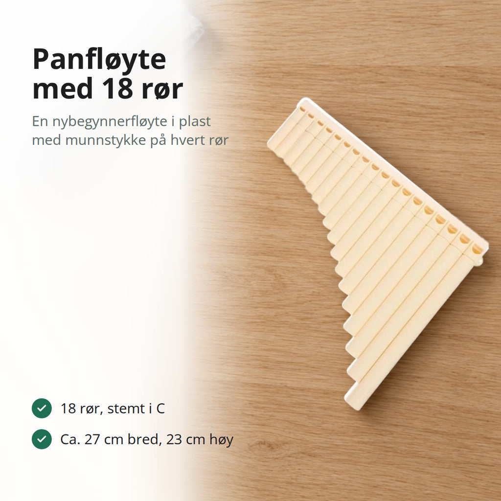 Lys beige panfløyte med 18 rør i plast, liggende på et bord i lys eik ved en grå linklut