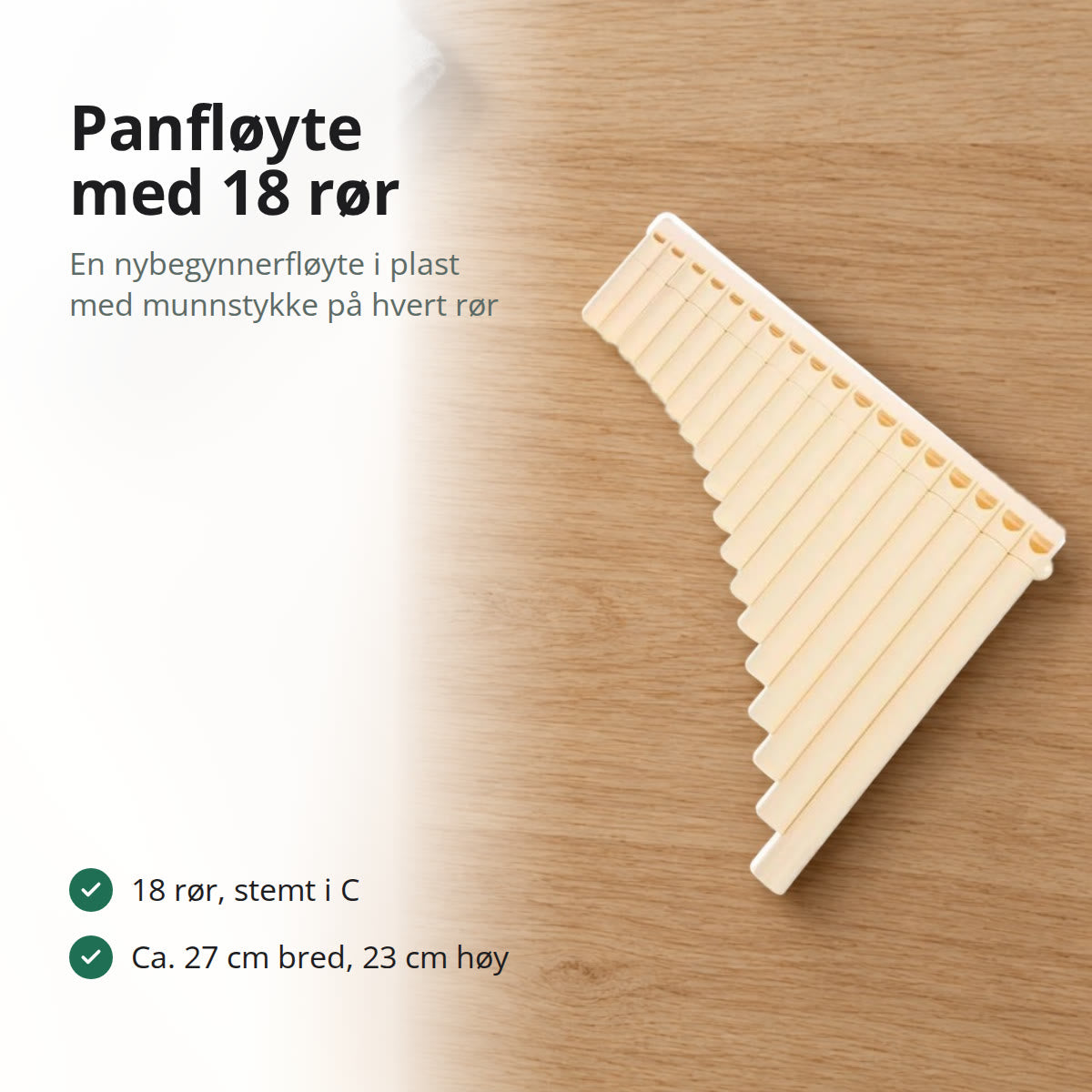 Lys beige panfløyte med 18 rør i plast, liggende på et bord i lys eik ved en grå linklut