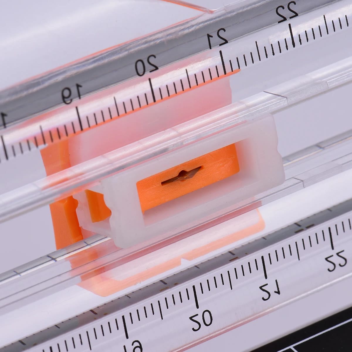 Nærbilde av det oransje knivhodet på den klare skinnen med målestokk i centimeter